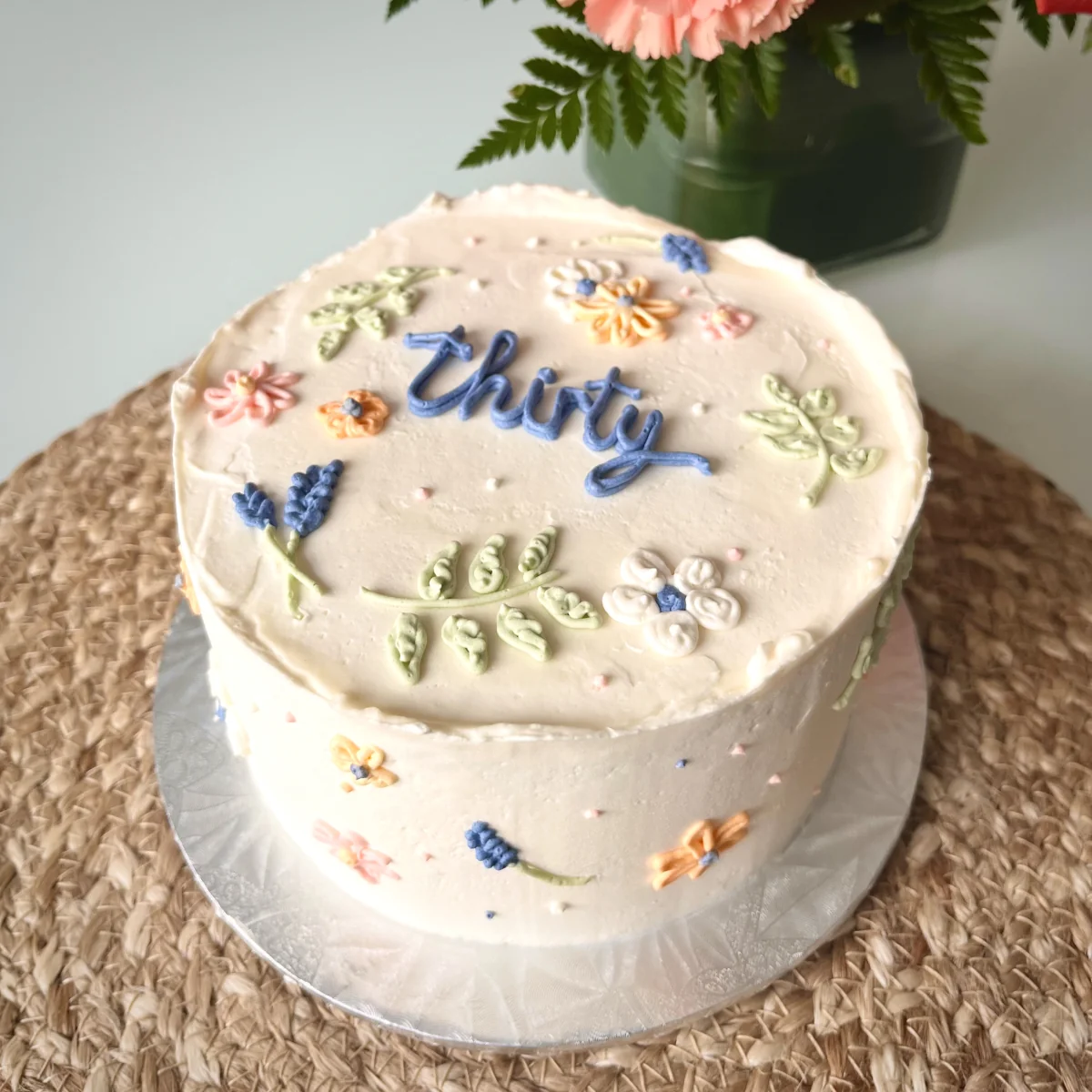 Cream 'Thirty' birthday cake with pastel piped wildflowers